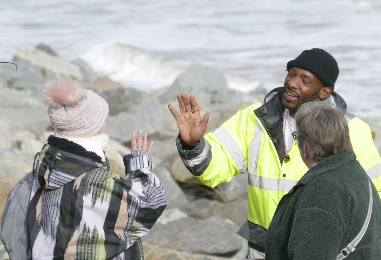A facilitator high-fiving a participant by the sea