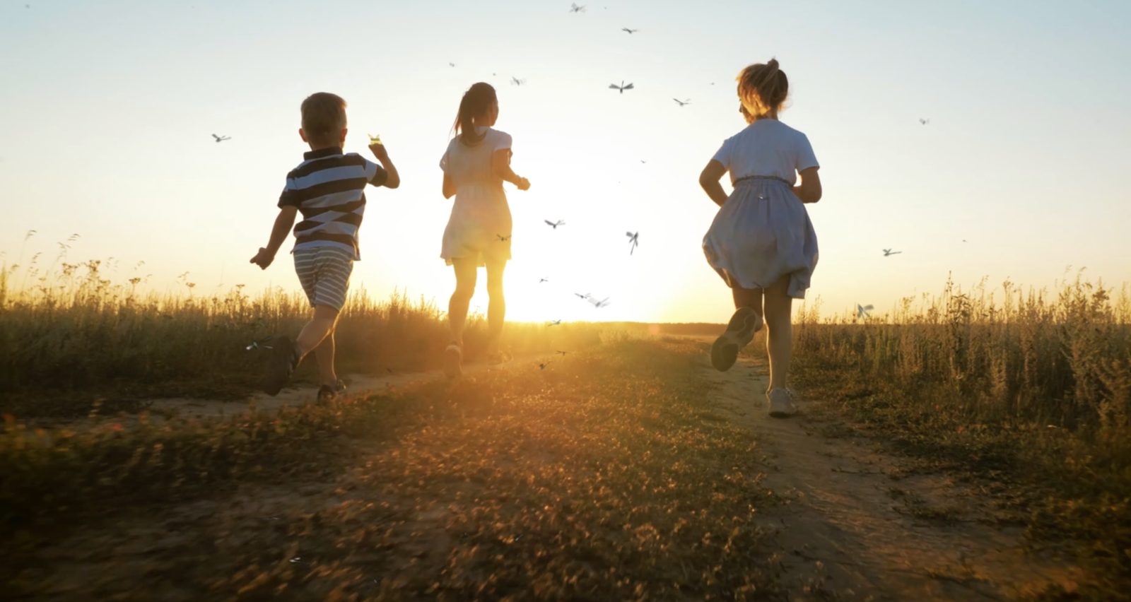 Children running along a Norfolk path at sunset